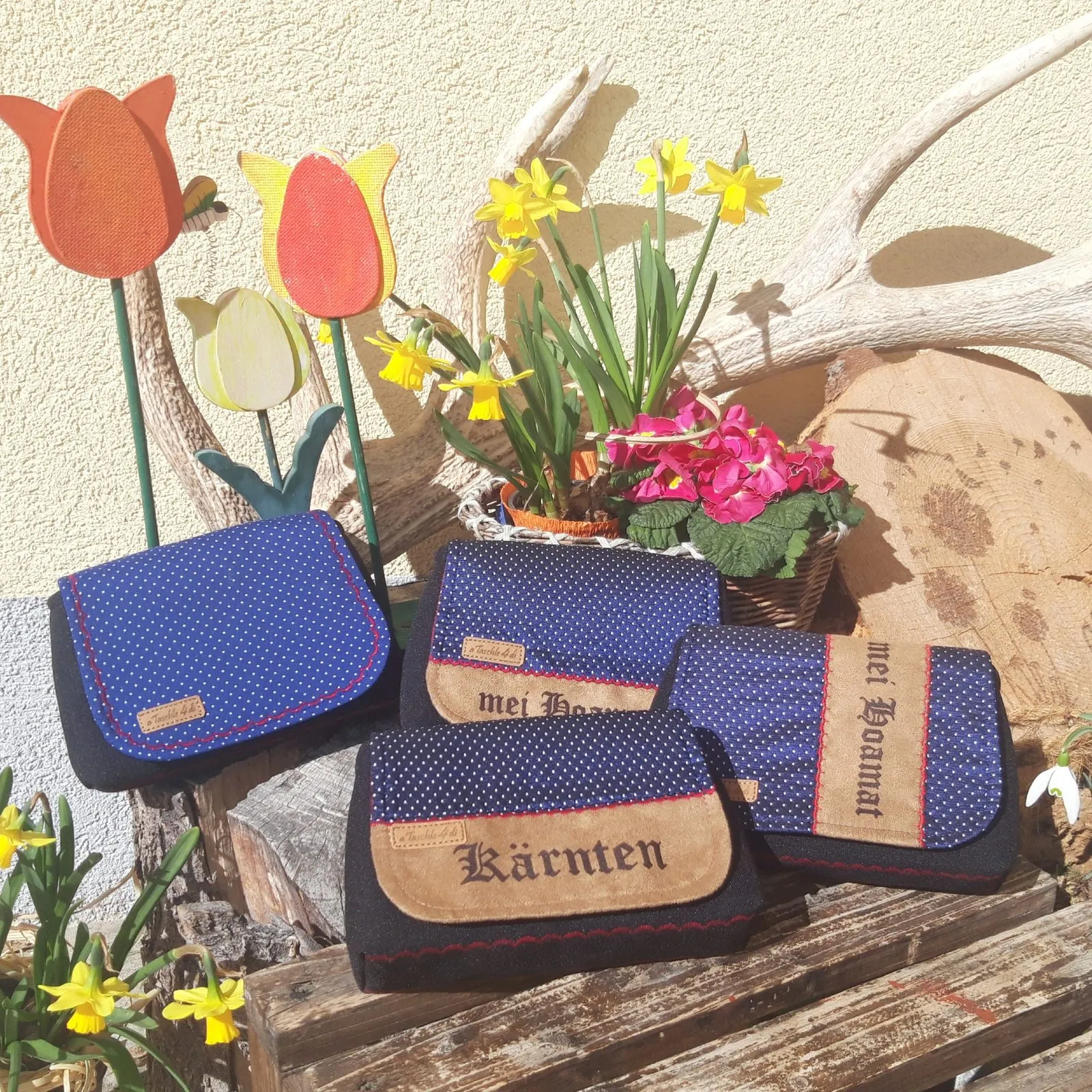 Blaue Taschen mit Kärnten-Aufschrift zwischen Frühlingsblumen