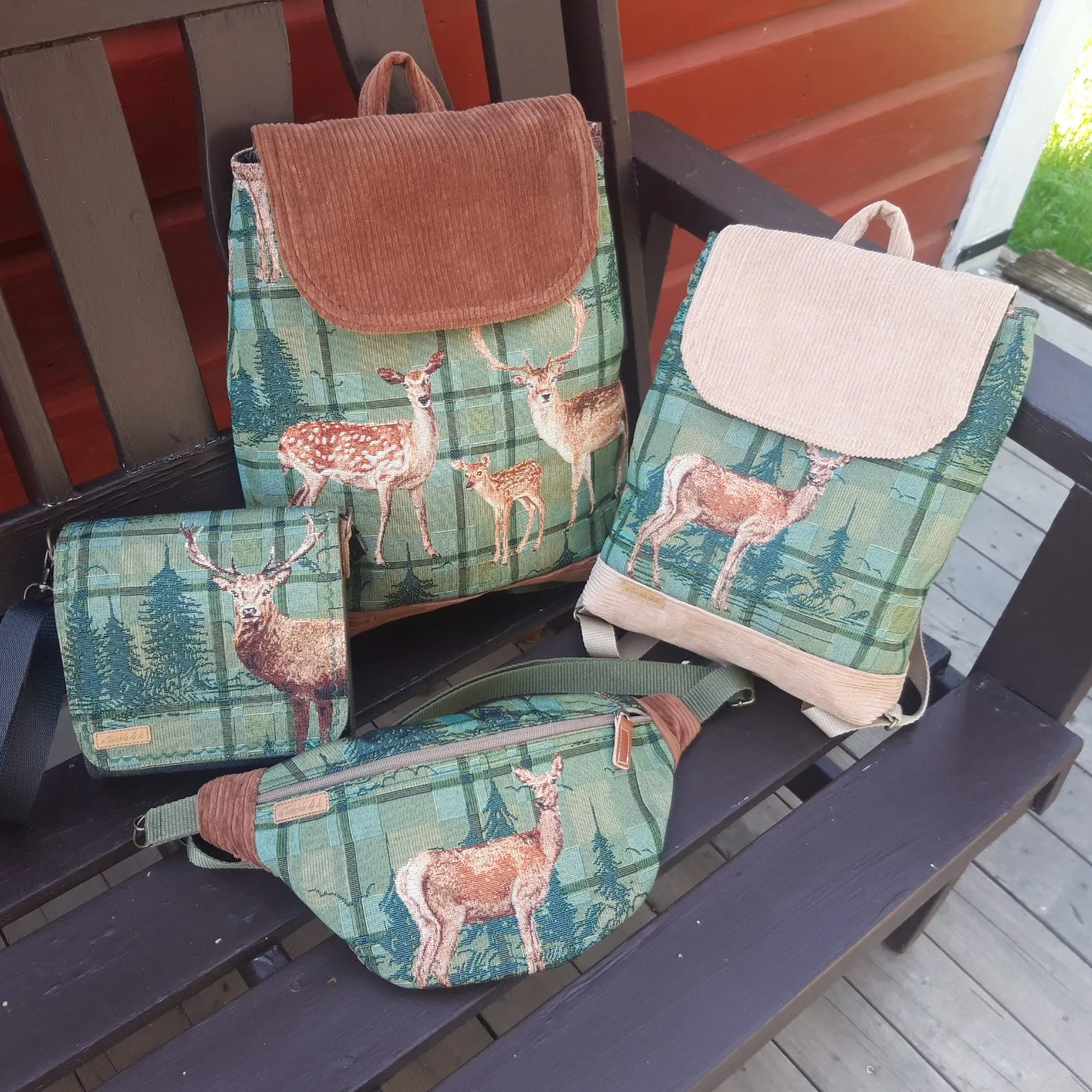 Rucksäcke, Tasche und Bauchtasche mit Hirsch- und Karomotiv auf einer Gartenbank