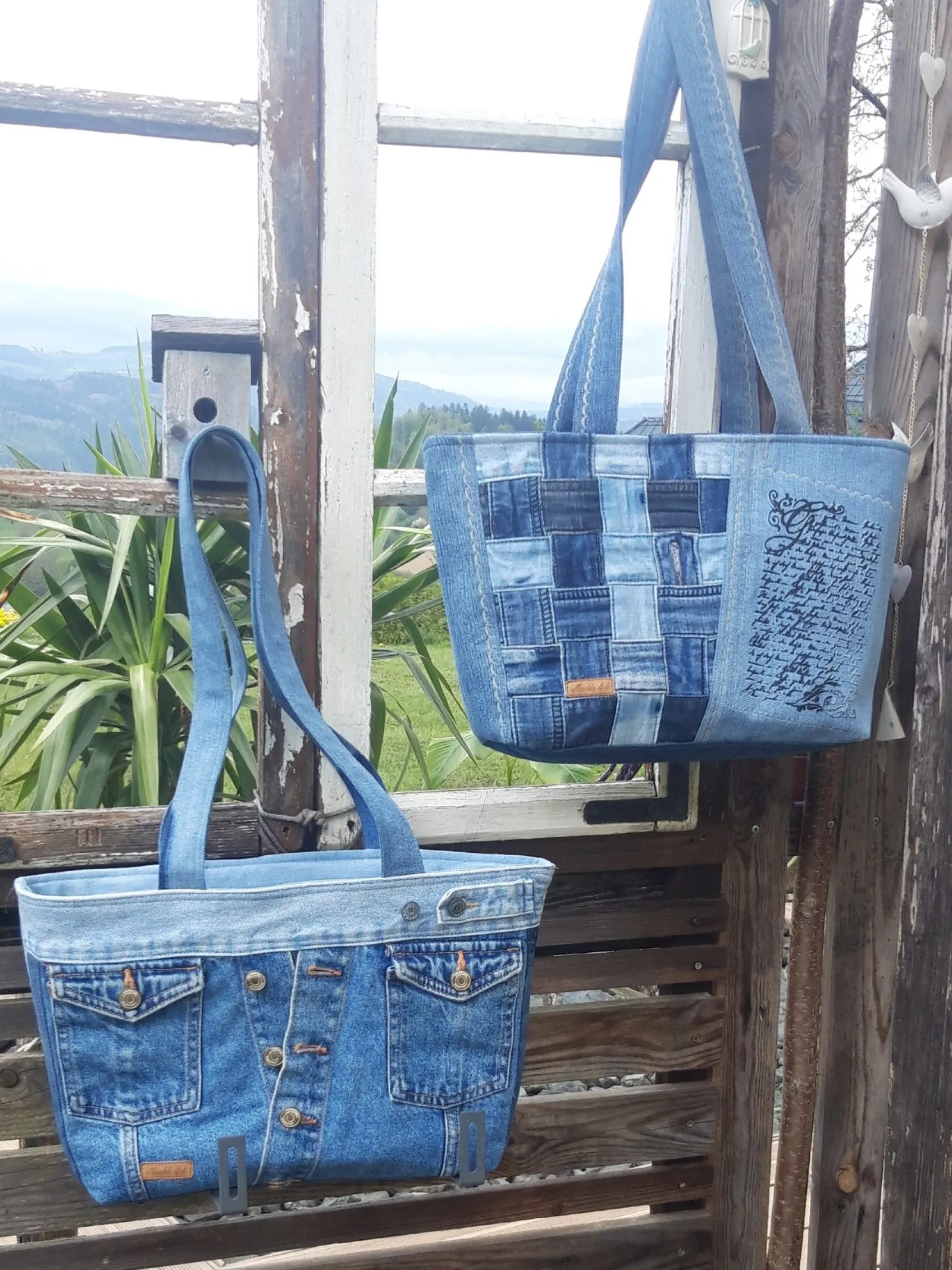 Zwei Shopper aus Jeans mit aufgesetzten Hosentaschen, an einem Holzgeländer hängend